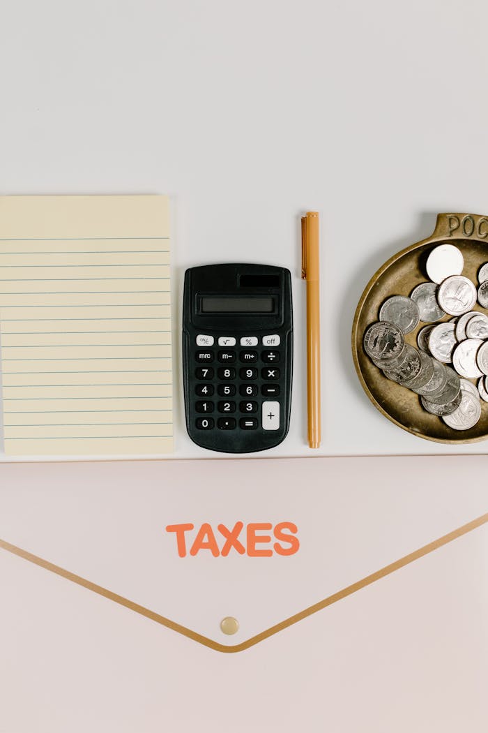 services-02 Flat lay of tax preparation tools including a calculator, notebook, and coins.